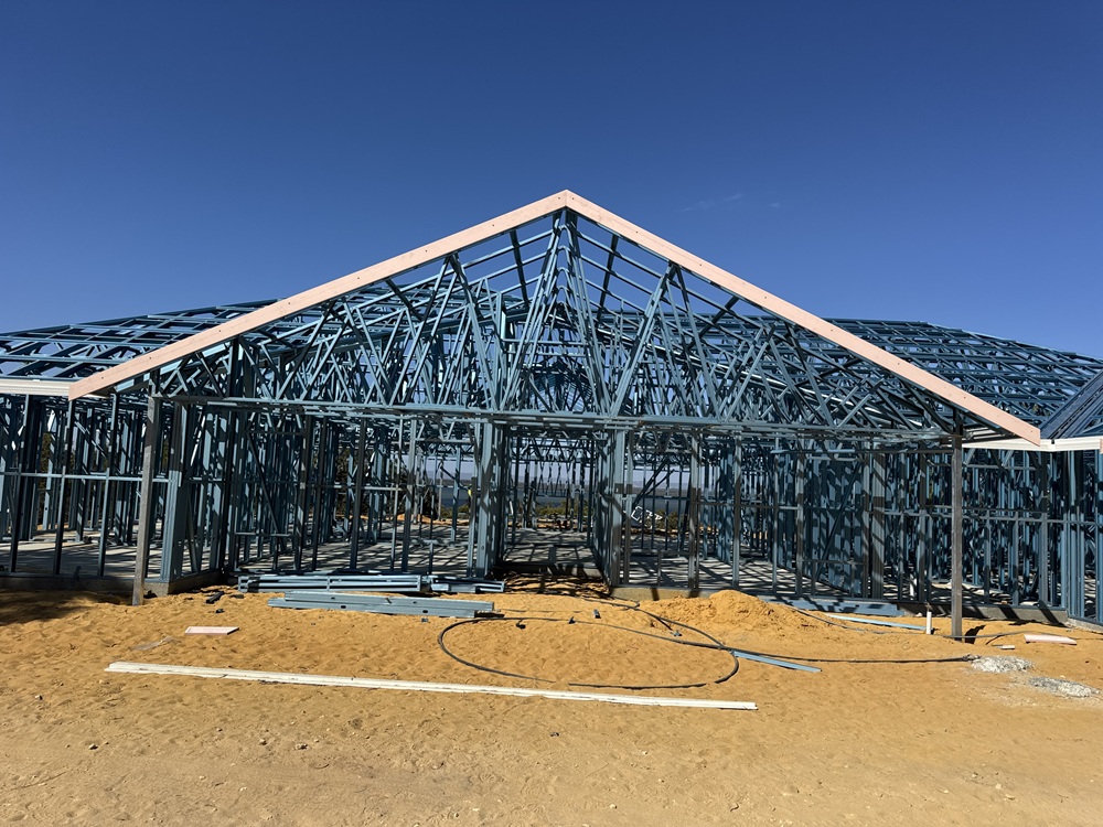 Steel wall frames and roof trusses on a house build under a clear blue sky in Western Australia